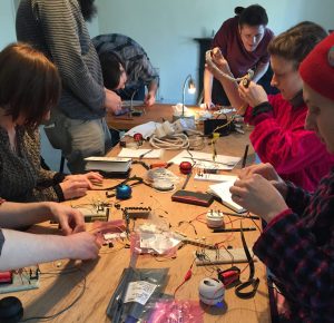 People around a table working with electronics components on prototype boards